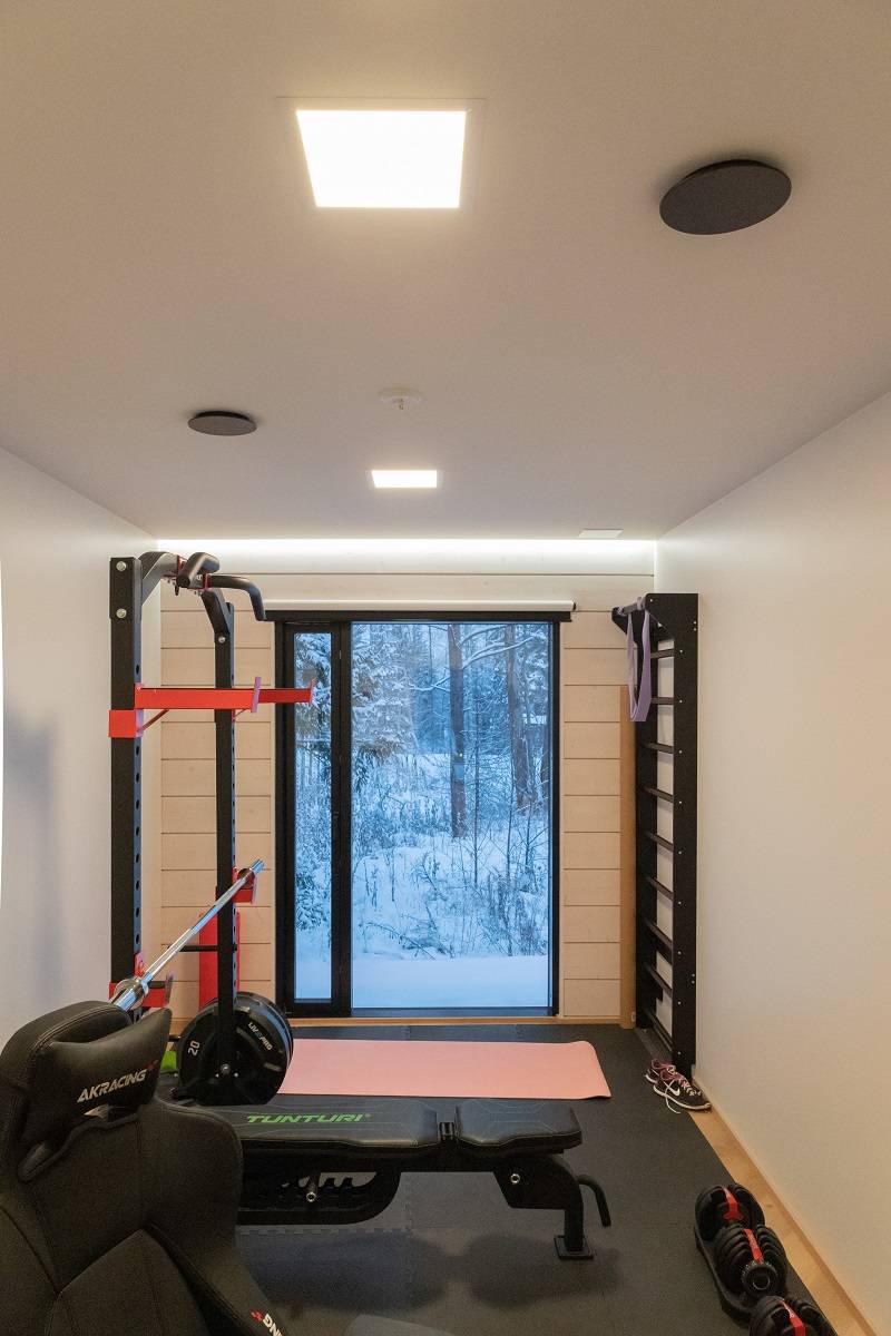 Dans une salle de loisirs, un éclairage général uniforme avec un luminaire carré Paneeli 300 et un éclairage indirect avec une bande LED sur la bordure mur/plafond pour compléter l'éclairage